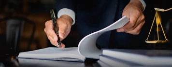 A hand holding a pen and about to write on a book