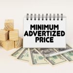 Business concept. On a white surface, cubes, dollars, a pen and a notepad with the inscription - Minimum Advertized Price Business concept. On a white surface, cubes, dollars, a pen and a notepad with the inscription - Minimum Advertized Price
