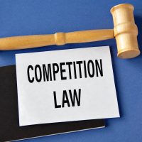 COMPETITION LAW - words on a white sheet on a black notebook with a judge's gavel in the background